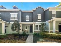 Charming townhome featuring neutral stucco, decorative trim, front porch with chairs, and manicured landscaping at 4521 Capital Blvd, St Cloud, FL 34769