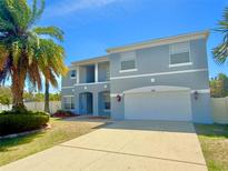 Charming two-story home featuring a blue exterior, well-manicured lawn, and a beautiful palm tree at 539 Lakeview Dr, Poinciana, FL 34759
