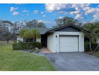 Charming single-story home featuring an attached one car garage, tropical landscaping and manicured lawn at 23 Buck Cir, Haines City, FL 33844