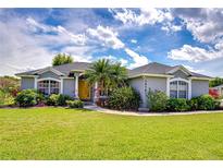 Charming one-story home with a well-manicured lawn, mature trees and inviting yellow front door at 3518 Remington Oaks Way, Lakeland, FL 33810