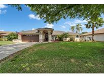 Charming single-story home with a well-manicured front lawn, mature trees, and an attached two-car garage at 7402 Gunstock Dr, Lakeland, FL 33809