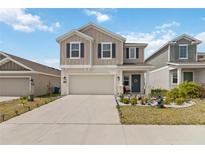 Inviting two-story home featuring a well-manicured lawn, neutral siding, and a two-car garage at 356 Loch Ct, Davenport, FL 33837