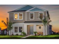 Charming two-story home featuring a covered front porch and manicured lawn at sunset at 2004 Marigold Aly, Winter Haven, FL 33884
