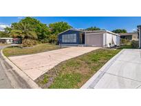 Charming blue home with a well-manicured lawn and extended driveway at 702 Turnberry Ln, Lady Lake, FL 32159