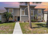 Charming two-story townhome with a well-manicured lawn, walkway, and lush tropical landscaping at 2116 Cypress Bay Blvd, Kissimmee, FL 34743