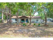 Charming single-story home with a blue door, brick exterior and mature trees in a serene setting at 3365 Bahama Ct, Lake Wales, FL 33898