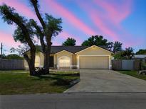 Charming single-Gathering home featuring a two-car garage and lush front lawn at dusk at 4889 Myrtle View N Dr, Mulberry, FL 33860