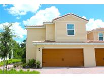 Charming two-story home featuring a terracotta roof, warm exterior paint, and a two-car garage at 607 Bay Leaf Dr, Poinciana, FL 34759