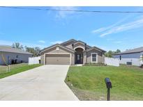 Charming single-story home with a well-manicured lawn, concrete driveway, and an attached two-car garage at 329 W Aster Ct, Poinciana, FL 34759