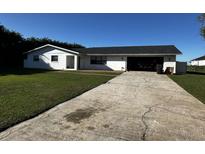 Charming single-story home featuring a spacious front lawn and open garage at 990 Keen Rd, Frostproof, FL 33843