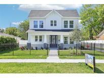 Charming two-story home featuring black wrought iron fence, inviting front porch, and manicured lawn at 214 E Harding St, Orlando, FL 32806