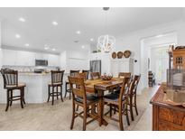 Bright dining area featuring an elegant chandelier, a wooden table with chairs, and access to the kitchen at 10367 Addison Shore Way, Oxford, FL 34484