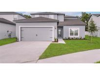 Charming home featuring a gray exterior, landscaped yard, and a two-car garage at 13275 Tula Loop, Astatula, FL 34705