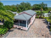 Aerial view of a charming home featuring a screened-in patio and a brick driveway surrounded by lush landscaping at 2991 Wood Duck Dr, Polk City, FL 33868