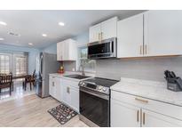 Modern kitchen with white cabinets, stainless steel appliances, tile backsplash, and an adjacent dining area at 820 Lamp Post Ln, Lakeland, FL 33809