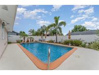 Backyard swimming pool and patio with palm trees and a white fence at 1545 Sailpoint Dr, Bartow, FL 33830