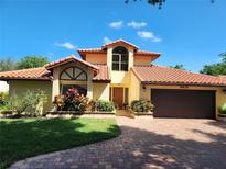 Charming home featuring a red tile roof, brick driveway, manicured lawn and lush landscaping at 8212 Borgia Ct, Orlando, FL 32836