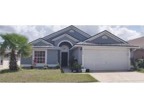 Charming single-story home featuring a well-manicured lawn and a two-car garage at 210 Cheshire Way, Davenport, FL 33897