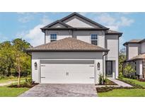 Charming two-story home boasts a white garage door, complemented by well-maintained landscaping and a brick driveway at 7756 Somersworth Dr, Kissimmee, FL 34747