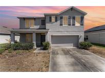 Charming two-story home features a gray exterior, well-maintained landscaping, and an attached two-car garage at 5597 Forest Ridge Dr, Winter Haven, FL 33881