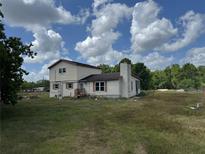 A two-story home has neutral siding, and a chimney sits on the stuccoed section at 10931 Pathfinder Trl, Lakeland, FL 33809