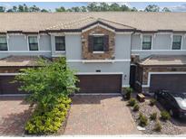 Beautiful townhome featuring a stone facade, brick driveway, and attached two-car garage at 1209 Payne Stewart Dr, Davenport, FL 33896