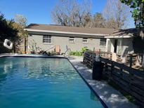The in-ground pool is steps away from the back of this gray brick home at 4707 Melody Ln, Lakeland, FL 33805
