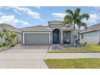 Charming single-story home features a well-manicured lawn, a brick driveway, and a cheerful blue front door at 140 Trinity Ridge Cir, Davenport, FL 33897