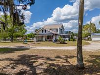 Charming two-story home with front porch, blue balcony and expansive lawn on a sunny day at 4145 Willis Rd, Mulberry, FL 33860
