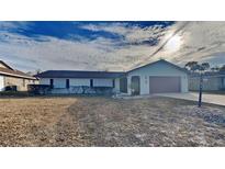 Charming single-story home with an attached garage and well-maintained front yard and a cloudy, blue sky at 699 Sullivan St, Deltona, FL 32725