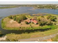Expansive aerial view of a unique home on an island, surrounded by a serene lake and lush greenery at 201 Lake Bonny E Dr, Lakeland, FL 33801