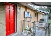 Exterior view of the home featuring a vibrant red front door and secure fenced entrance to the property at 2341 Weber St, Lakeland, FL 33801