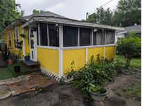 Charming, yellow exterior showcasing a screened-in porch with decorative lighting and landscaping at 730 Citrus St, Orlando, FL 32805