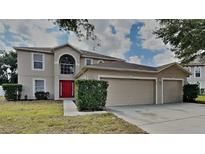 Charming two-story home features a red front door and a spacious three-car garage at 105 Evergreen Dr, Auburndale, FL 33823