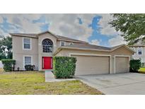 Two-story home featuring a two-car garage, manicured lawn, bright red front door, and neutral exterior color at 105 Evergreen Dr, Auburndale, FL 33823