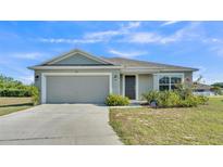 Charming single-story home with a two-car garage, neatly landscaped front yard, and neutral color palette at 513 Kimbrel Ct, Haines City, FL 33844