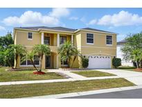Stunning two-story home with manicured lawn, mature palm trees, and a white two car garage at 2523 Jasmine Trace Dr, Kissimmee, FL 34758