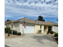 Charming single-story home with attached garage, manicured landscaping, and an American flag at 2807 Leicester Ter, The Villages, FL 32162