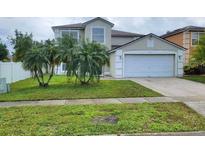 Two-story home featuring a two-car garage, front lawn with palm trees, and neutral-colored exterior at 1416 Aguacate Ct, Orlando, FL 32837