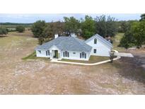 Well maintained white home with dark shutters, covered entryway, and landscaping on a large property at 24025 Ranch Rd, Astatula, FL 34705