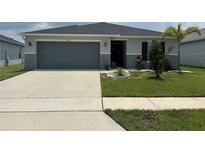 Charming single-story home with a well-manicured lawn, two-car garage, and a welcoming entrance at 1351 Pompay Dr, Davenport, FL 33896