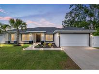 Beautiful well-lit home at sunset, featuring manicured yard, and attached two-car garage at 6873 Sw 131St Pl, Ocala, FL 34473