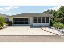 Charming home featuring a screened in porch, wide driveway, and manicured landscaping at 7040 Tamarind Dr, Lake Wales, FL 33898
