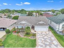 Well-maintained home with lush landscaping, charming flowerbeds, and a unique patterned driveway at 1709 Latta Ct, The Villages, FL 32162