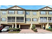 Townhouse with a one-car garage, brown shutters, a screened balcony, and neat landscaping at 2352 Grand Central Pkwy # 18, Orlando, FL 32839