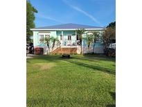 Charming beach house with a blue exterior, inviting porch, and lush green lawn at 166 Catfish St, Haines City, FL 33844
