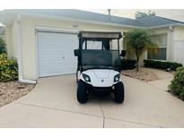 Charming home exterior featuring a golf cart parked near the garage and well-maintained landscaping at 1087 Jackson St, The Villages, FL 32162