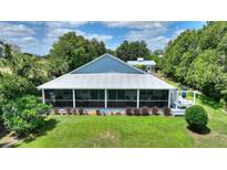 Charming screened porch overlooks the lush backyard with mature landscaping and a metal roof at 1395 S Lake Reedy Blvd, Frostproof, FL 33843