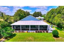 Charming home featuring a metal roof, spacious screened porch, and well-manicured lawn at 1395 S Lake Reedy Blvd, Frostproof, FL 33843