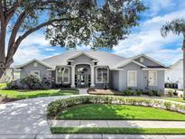 Beautiful single-story home with a gray exterior, manicured lawn, circular driveway, and mature landscaping at 2161 Longleaf Cir, Lakeland, FL 33810
